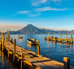 Fotografía del embarcadero de madera del lago Atitlán con el volcán al fondo del paisaje