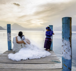Pareja de recién casados sentados en embarcadero de madera en el lago Atitlan Guatemala
